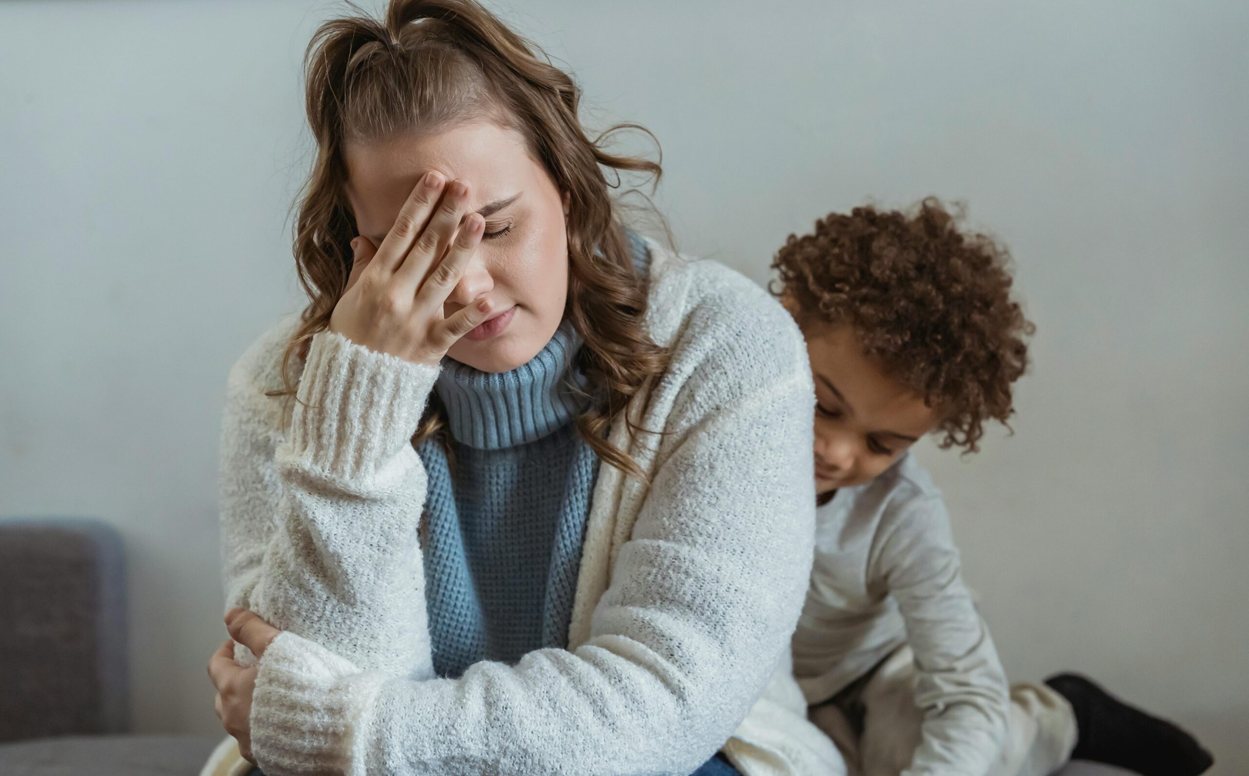 Tired mother sitting beside her young son at home after a difficult moment, showing family stress and emotional strain