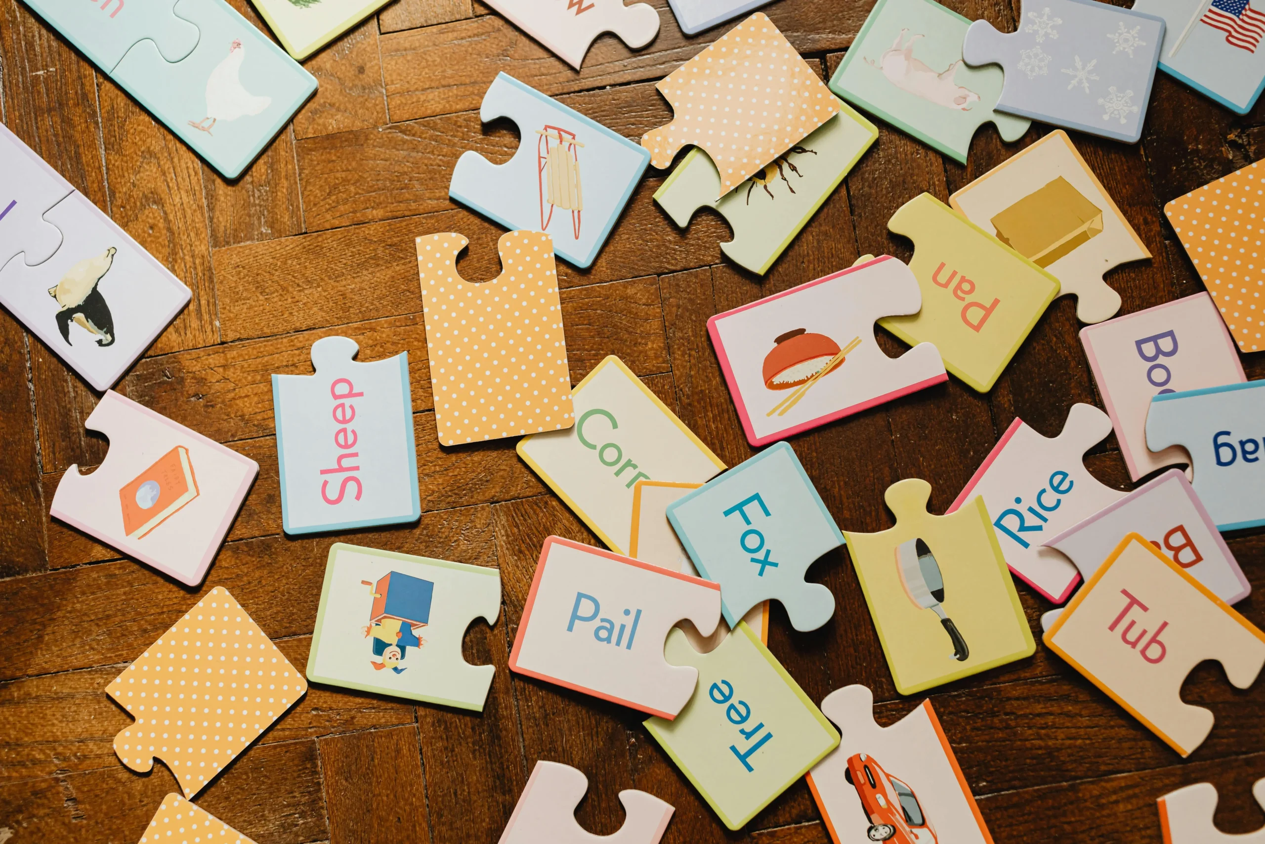 Scattered children’s puzzle pieces on a wooden floor, representing toy play and behaviour patterns.